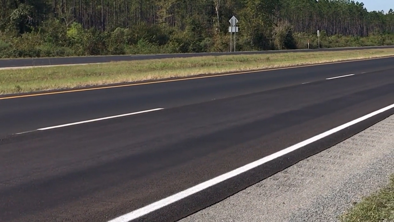 Close up of a four-lane newly paved asphalt highway without traffic.