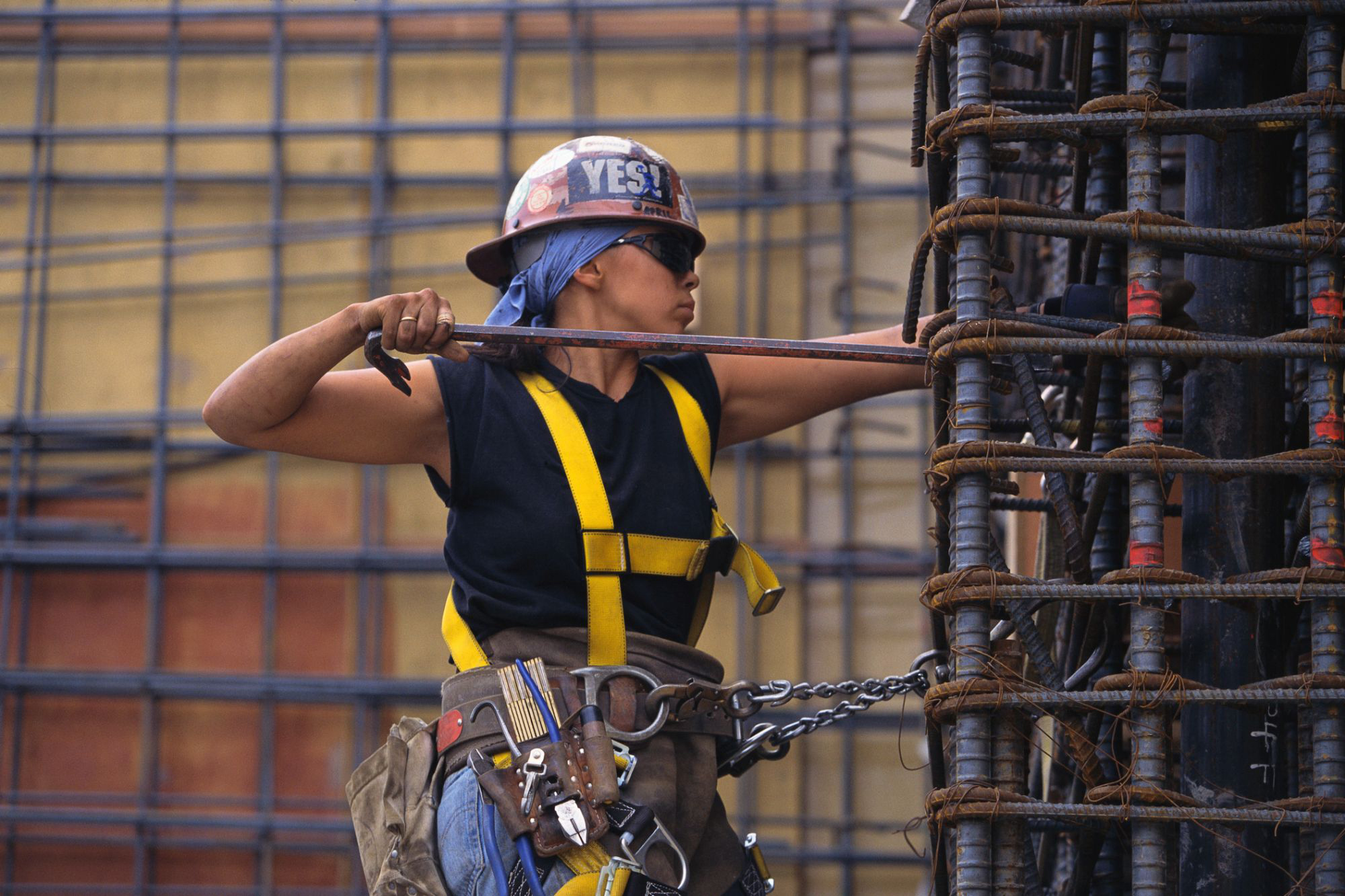 Woman construction worker with hard hat installing rebar on a column.