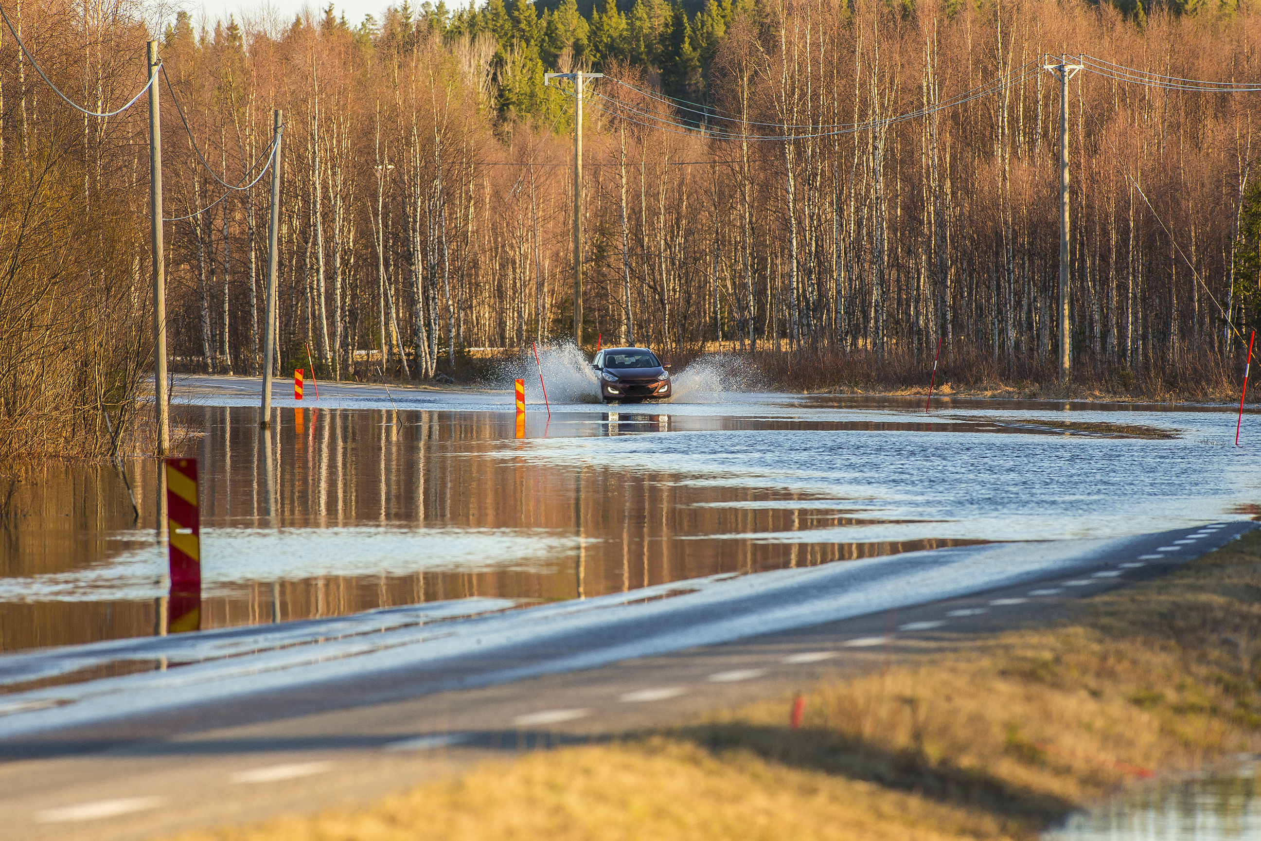 A car driving on a road half submerged in flood water