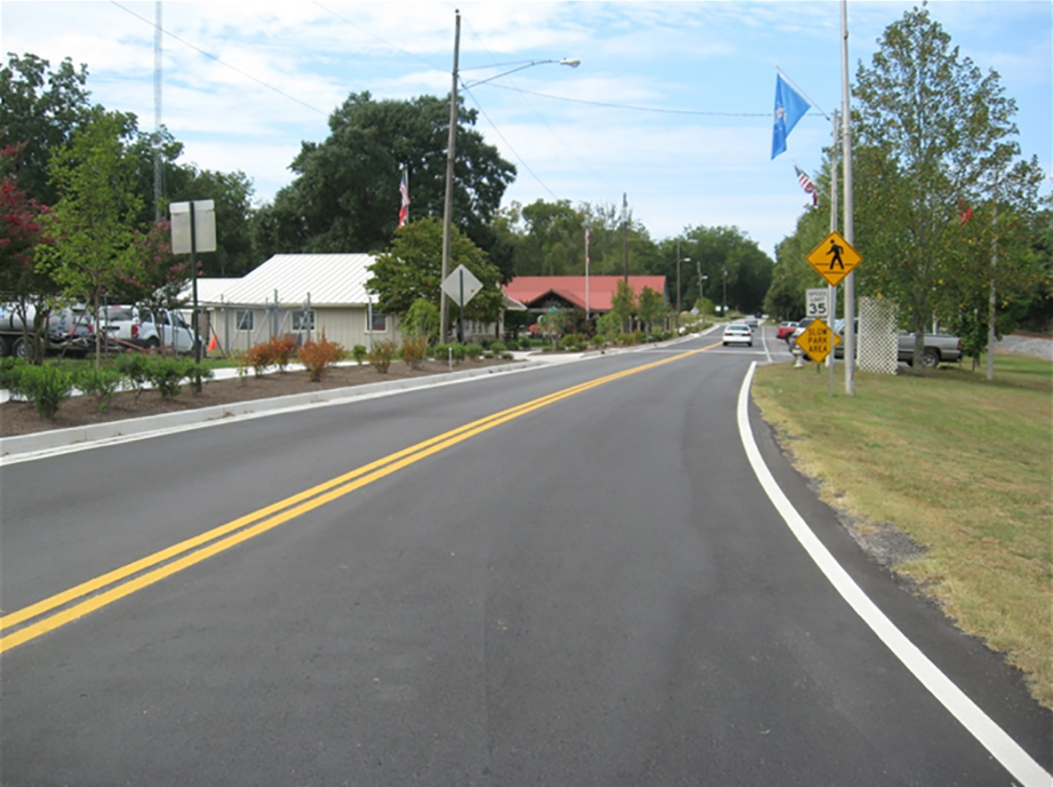Newly paved two-lane road with newly built curb on left side of the image.