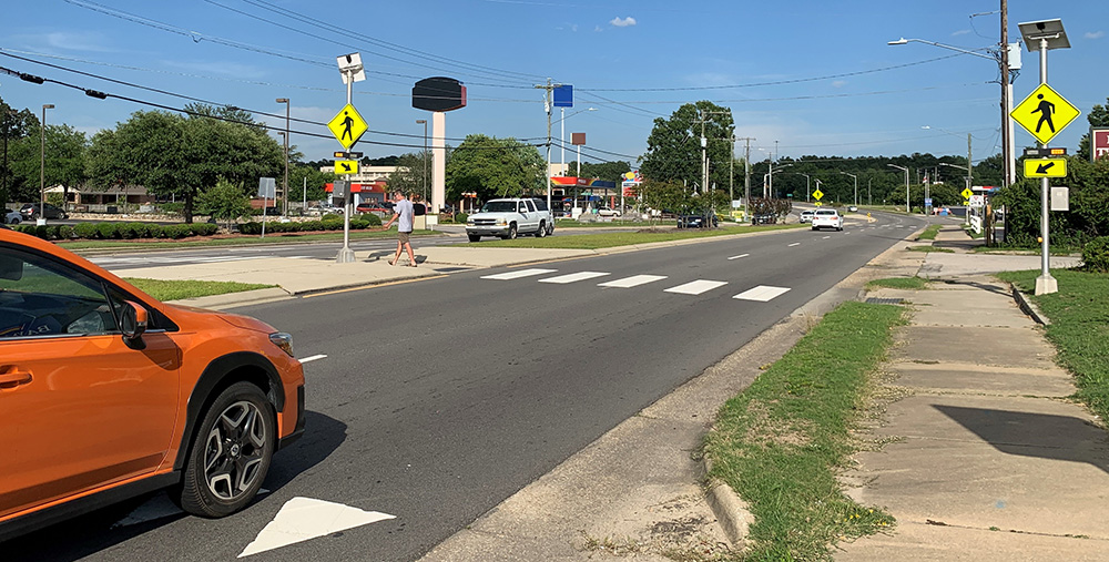 Car approaching RRFBs at a crosswalk.