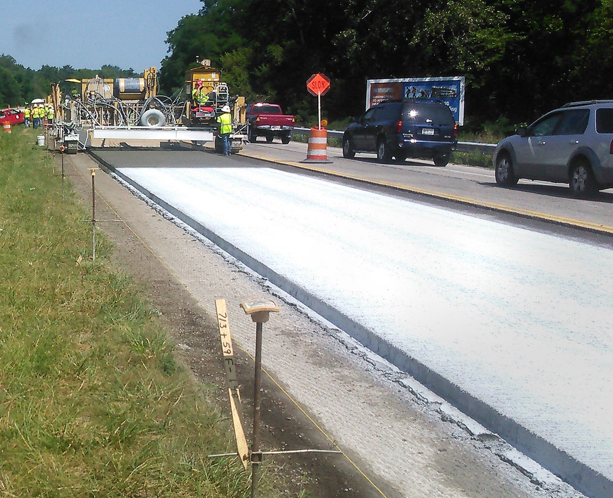 Crew paving road using concrete overlay mixures.