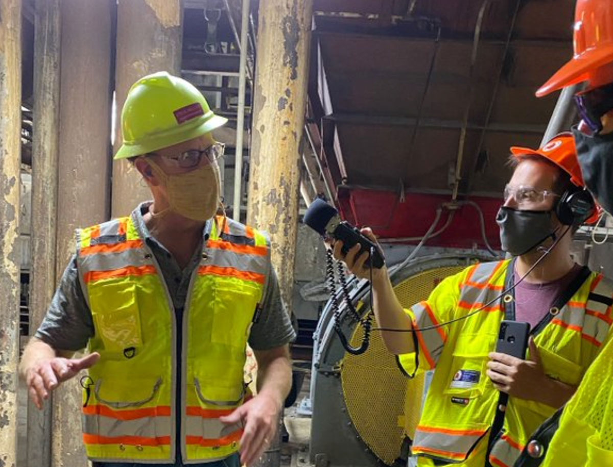 Person, wearing safety equipment, being interviewed by another set of people, also wearing safety equipment.