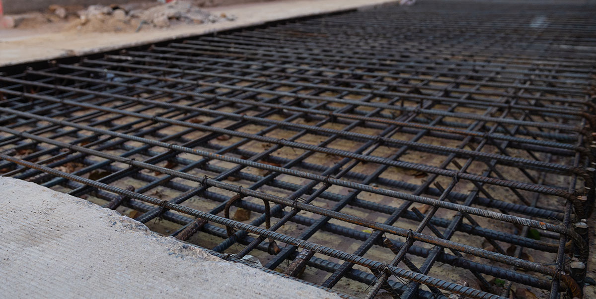 Roadway section under construction. Exposed rebar criss-crosses the section awaiting concrete.