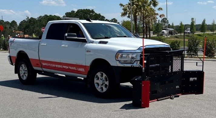 Pickup truck with angled 'scoop' connected to front with a hydraulic lift. Scoop shape directs debris to right.