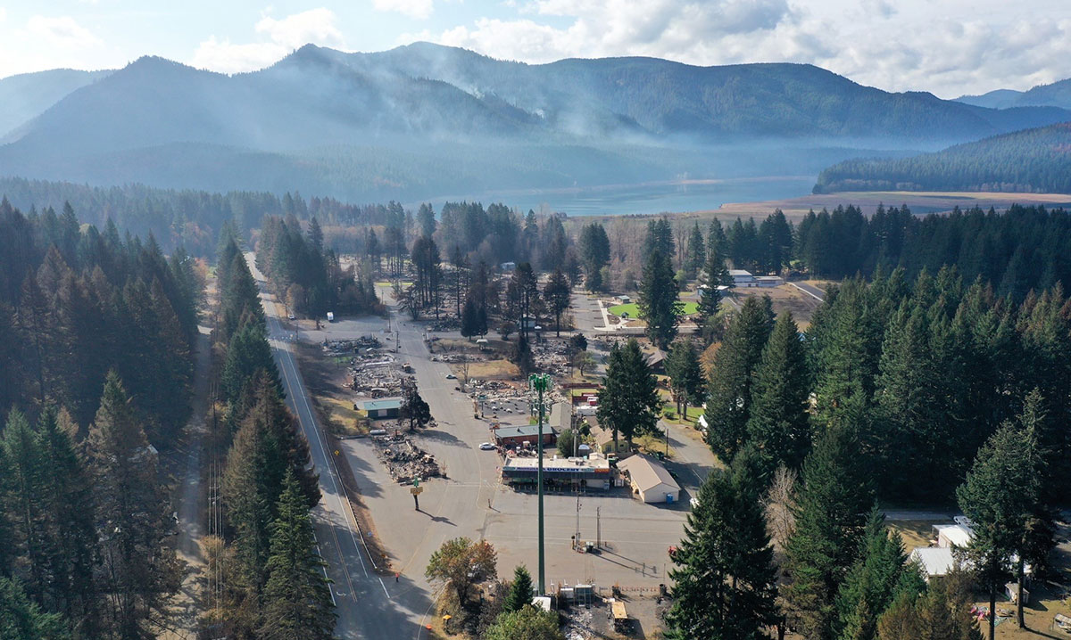 Aerial photograph of a town with severe wildfire damage, surrounded by trees.