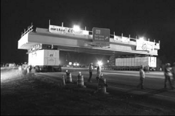 crews move the prefabricated bridge structure into position at night.