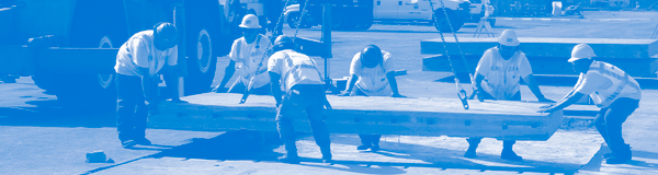 Photograph showing construction workers lowering a PCC slab into place.