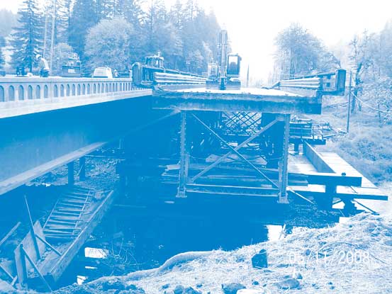 In the Oregon project, the old bridge is the steel truss structure at right, seen after being slid onto temporary piers. The new bridge is at left.