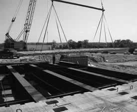 Photograph of a crane lifting a precast panel onto the bridge to span the steel girders.