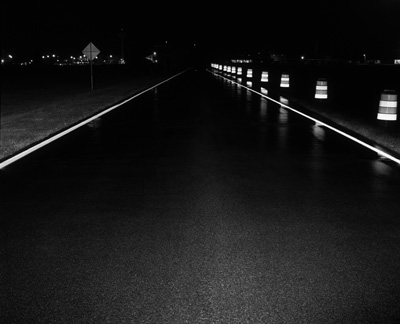 The pavement marking system, developed by 3M, is shown in use on a roadway construction zone at night. The photograph highlights the high amount of reflectivity of the marking system.