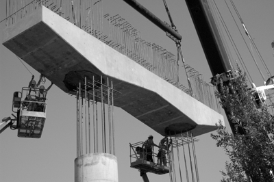 Workers place a precast cap beam on a bridge project in Washington State.