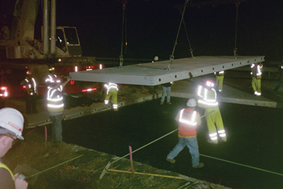  Photo Caption: Crews install precast concrete pavement  slabs at night on a rapid pavement rehabilitation project in Virginia.