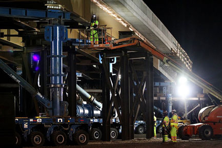 Crew members prepare to move the Sam White Bridge with self-propelled modular transporters.