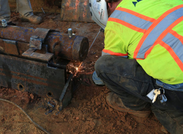 Crew member welds a hydraulic pump used in the slide.