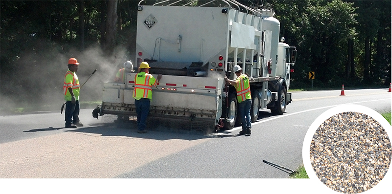 Photo of crews apply high-friction surface treatment to enhance safety on a roadway curve. Up close: High-friction surface treatment consists of a binder topped with specially engineered aggregate, in this case calcined bauxite aggregate. Credit: Delaware Department of Transportation.