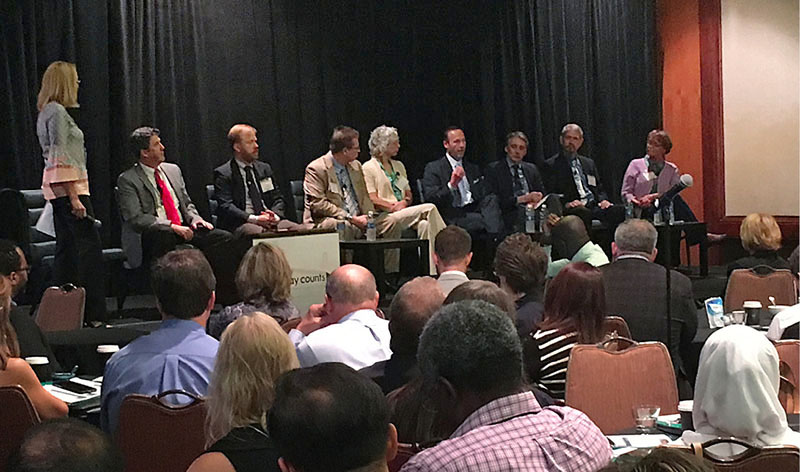 Photo of people in a conference hall watching transportation executives participate in a panel discussion.