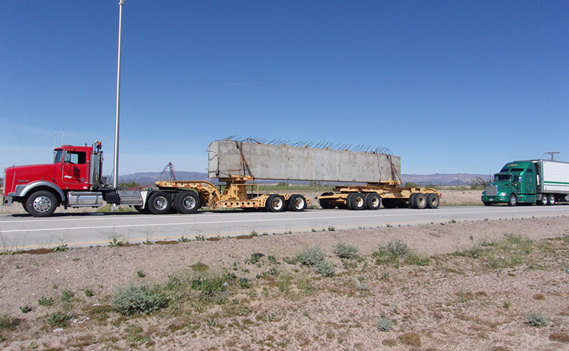 Photo of a truck carrying a bridge component on a highway.