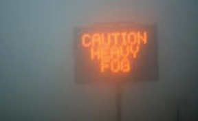 Road weather message that reads “Caution Heavy Fog”