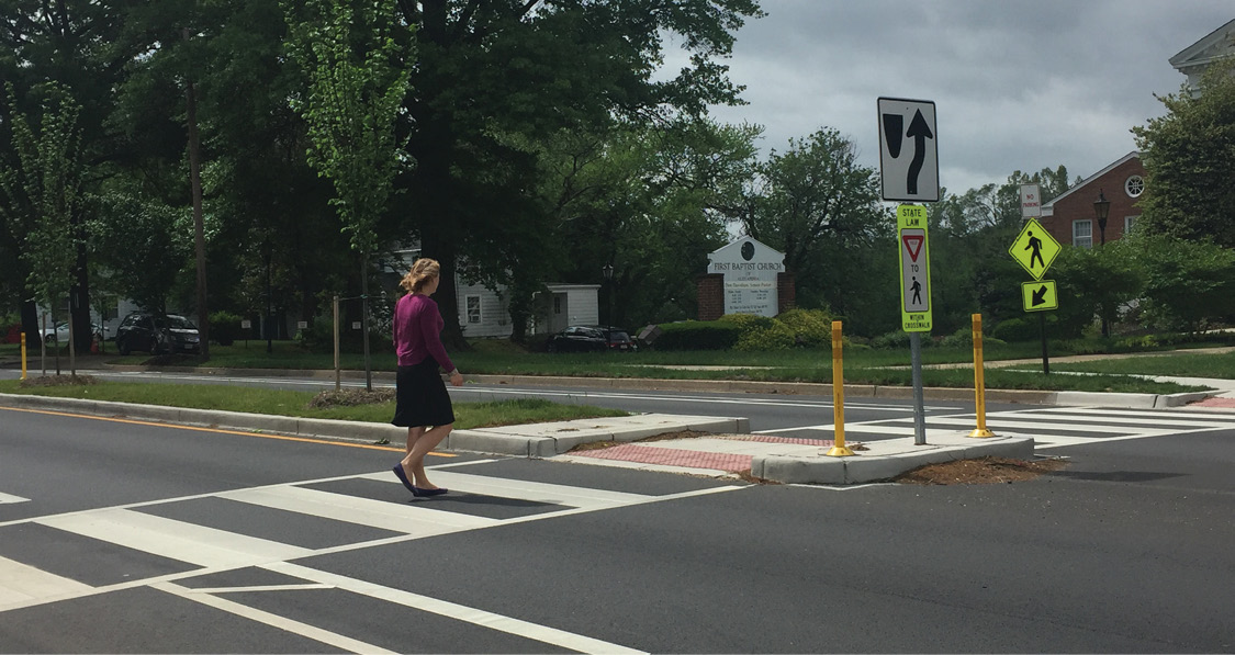 Photo of pedestrian in a crosswalk approaching a refuge island.