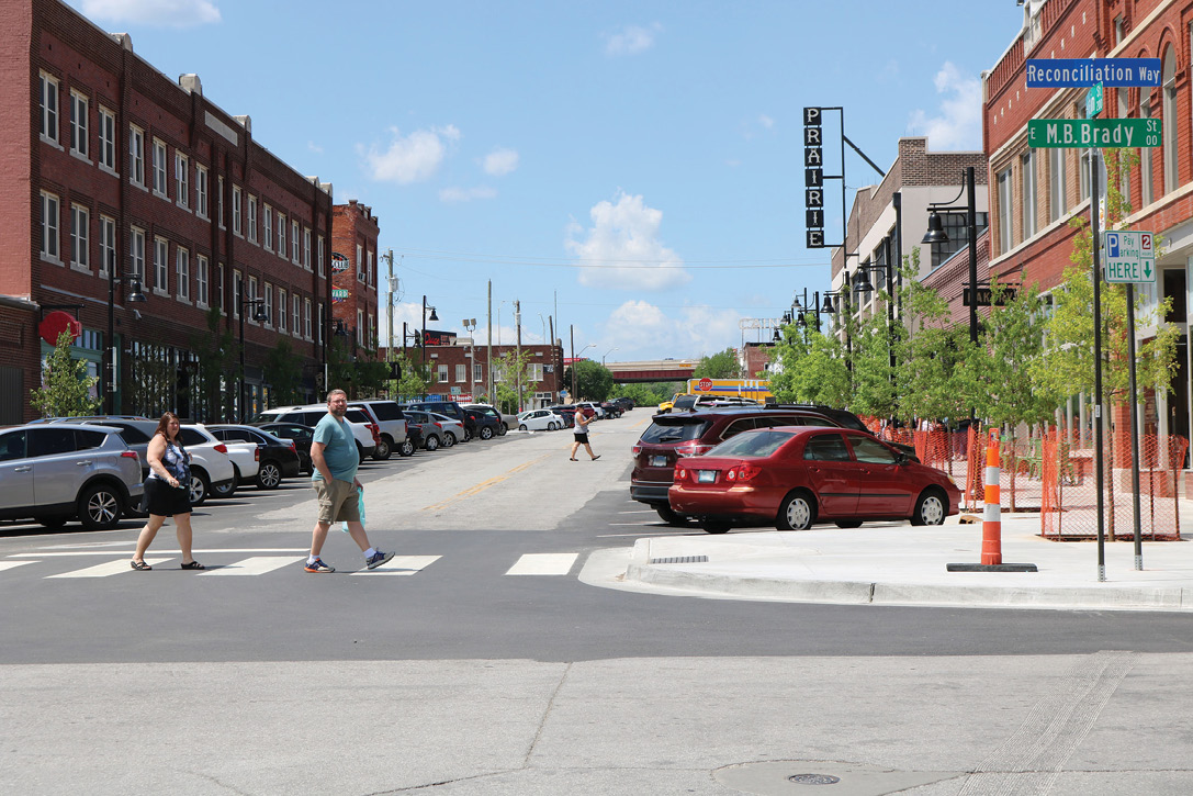 Two pedestrians in a crosswalk walking toward a curb extension.