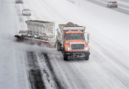 Plow and salt spreader on snow-covered highway.