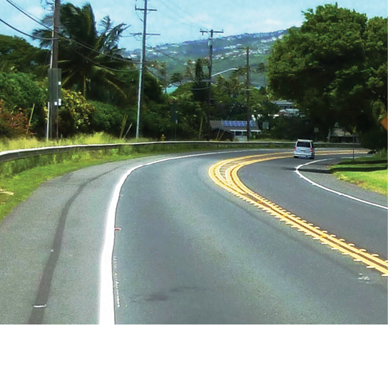 Photo of car on rural roadway curve with safety countermeasures.