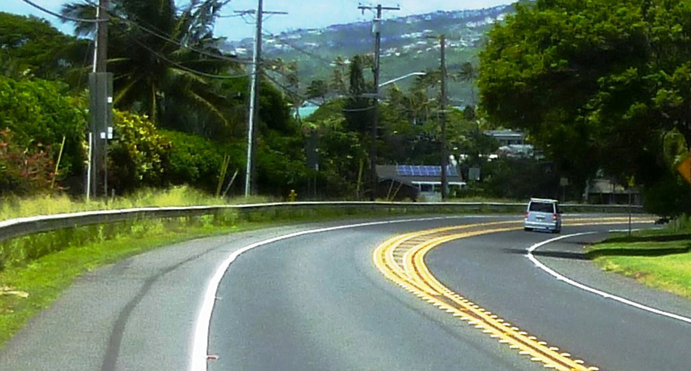 Photo of car on rural roadway curve with safety countermeasures.