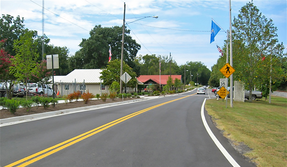 A newly striped two-lane asphalt roadway passing through a small town in Georgia.