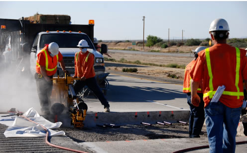 Workmen using equipment to cut road