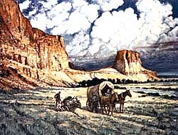 In a desolate landscape, a driver stands and looks down at his stranded automobile as he is passed by a covered wagon.