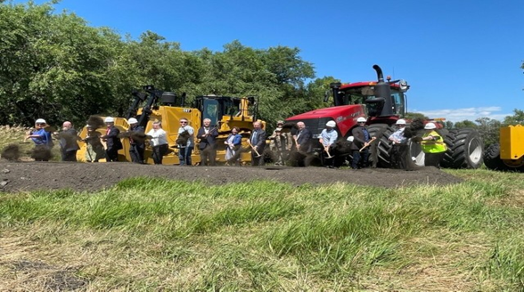 A group of US Army Corps of Engineers leaders with shovels broke ground and  standing next to a tractor