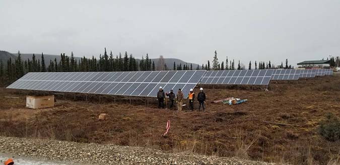 Five men standing in front of the Hughes solar-diesel microgrid.