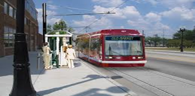 A proposed Omaha's streetcar red and white train on a street with people waiting at the station