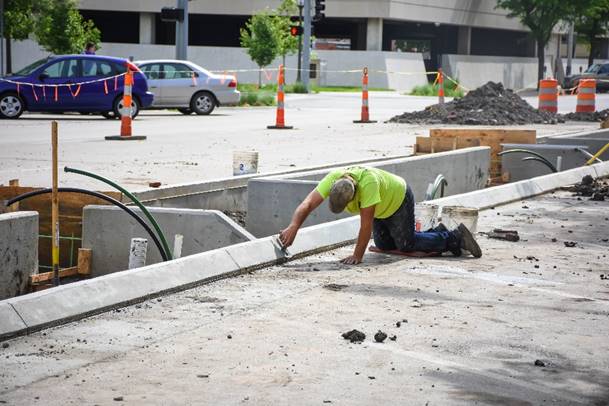 a kneeling worker hand-finishes a curb