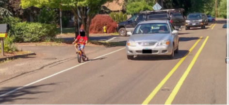 Car on road with bicyclist on the left.