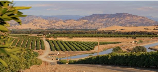 Panoramic photo of water in a valley and a backdrop of mountains.