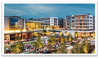 Mosaic District; Fairfax County - OCR. A lively scene of mixed-use buildings, people milling around, and some traffic passing by the cluster of buildings.