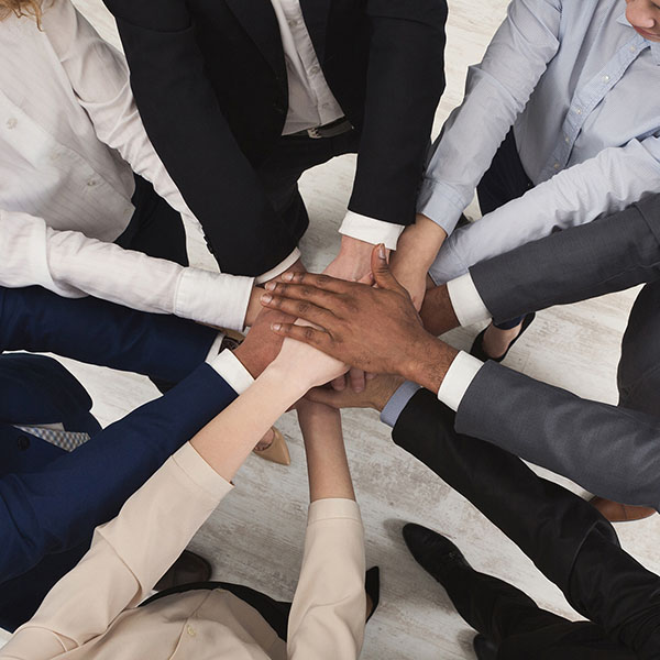 An overhead view of 7 people overlapping their hands to show teamwork