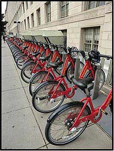 Picture 5. Graphic. The picture shows a row of bikes parked at a bikeshare facility along a sidewalk.
