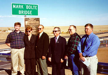 Photo-Group of people standing on bridge in front of "Mark Bolte Bridge" sign