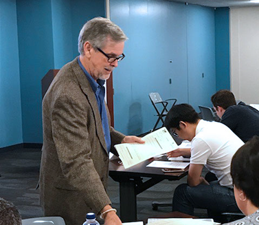 Brian Betlyon holding papers in front of class on Transportation Program Management (TPM)