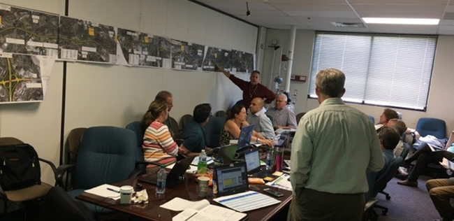 David Unkefer points to photos on a wall as he leads a Construction and Project Management session