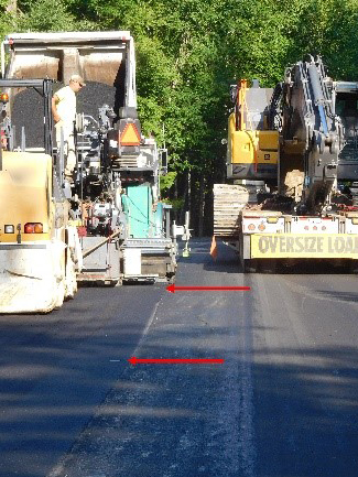Asphalt with heavy equipment and two red arrows in the center.