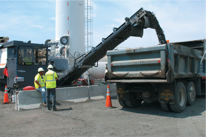 Machine dumping asphalt into a dump truck.