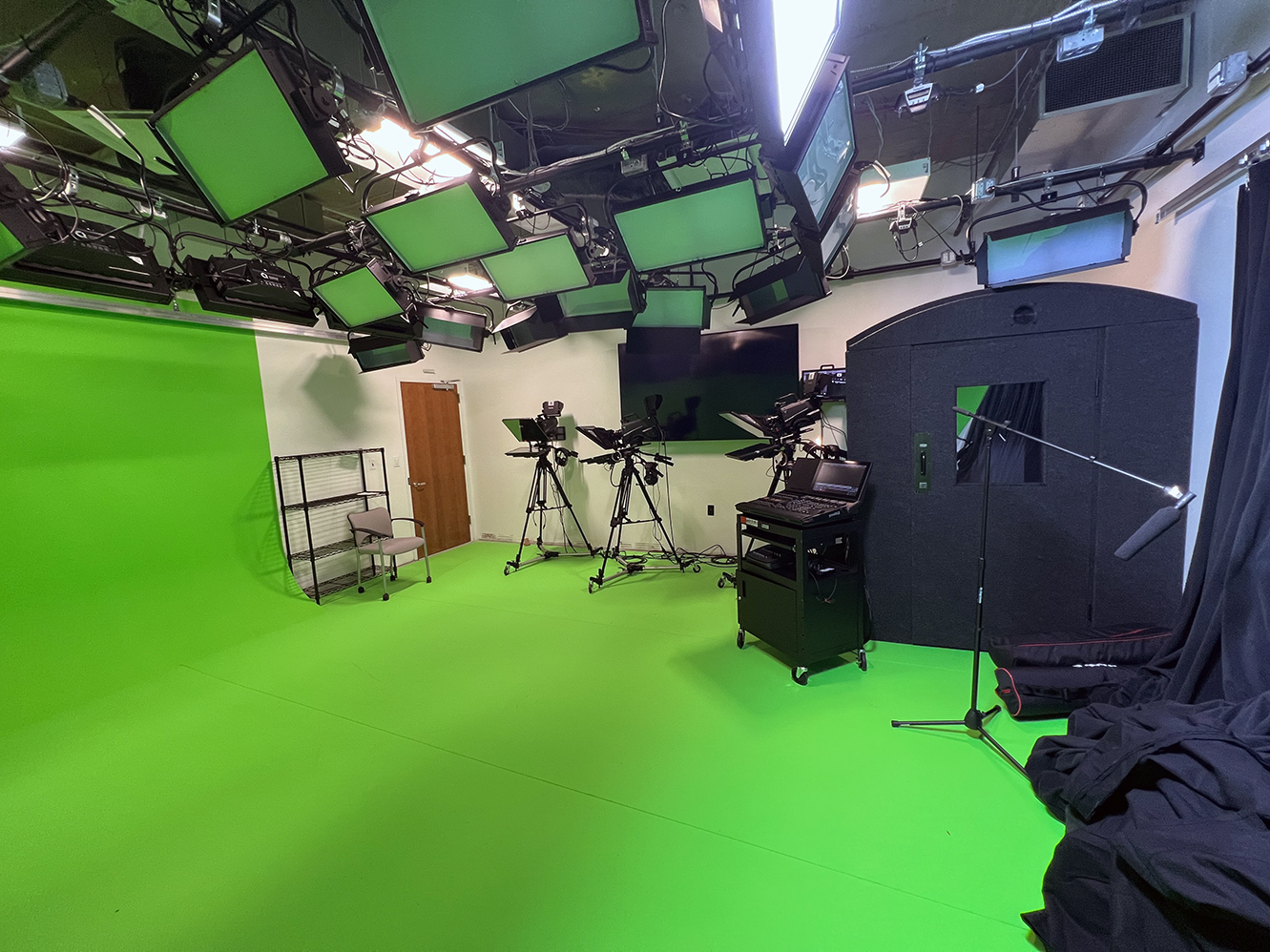 A green production room with cameras and microphones.
