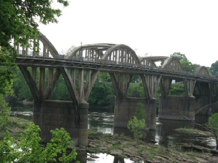 This image shows a multi-arched concrete bridge located over a river.