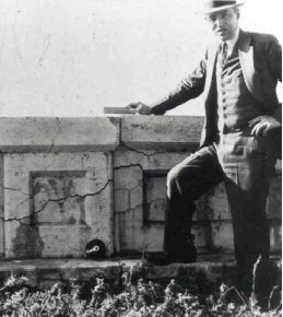 Photograph of Thomas Stanton, standing next to a large concrete barrier exhibiting severe cracking