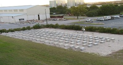 Outdoor exposure site at the Univeristy of Texas. This picture shows aerial view of multiple rows of concrete blocks on a large tract of gravel surrounded by grass