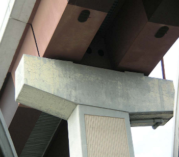 This image shows a close up view of the underside of a bridge structure, a concrete bent cap supporting a steel bridge beam. The bent cap is showing excessive map cracking and is stained in yellow, most likely from paint, in and around the edges of the cap